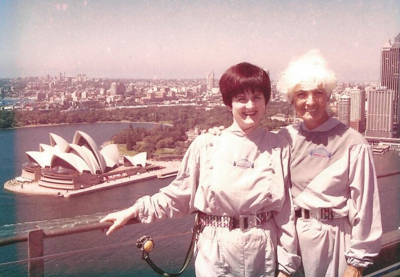 Ann MacKenzie is shown with the Sydney Opera House in the background, standing atop the Harbour Bridge, alongside her niece.