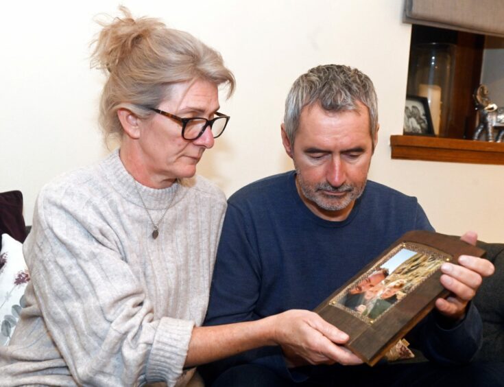 Cath Fraser and Graeme Fraser looking at a picture of their son