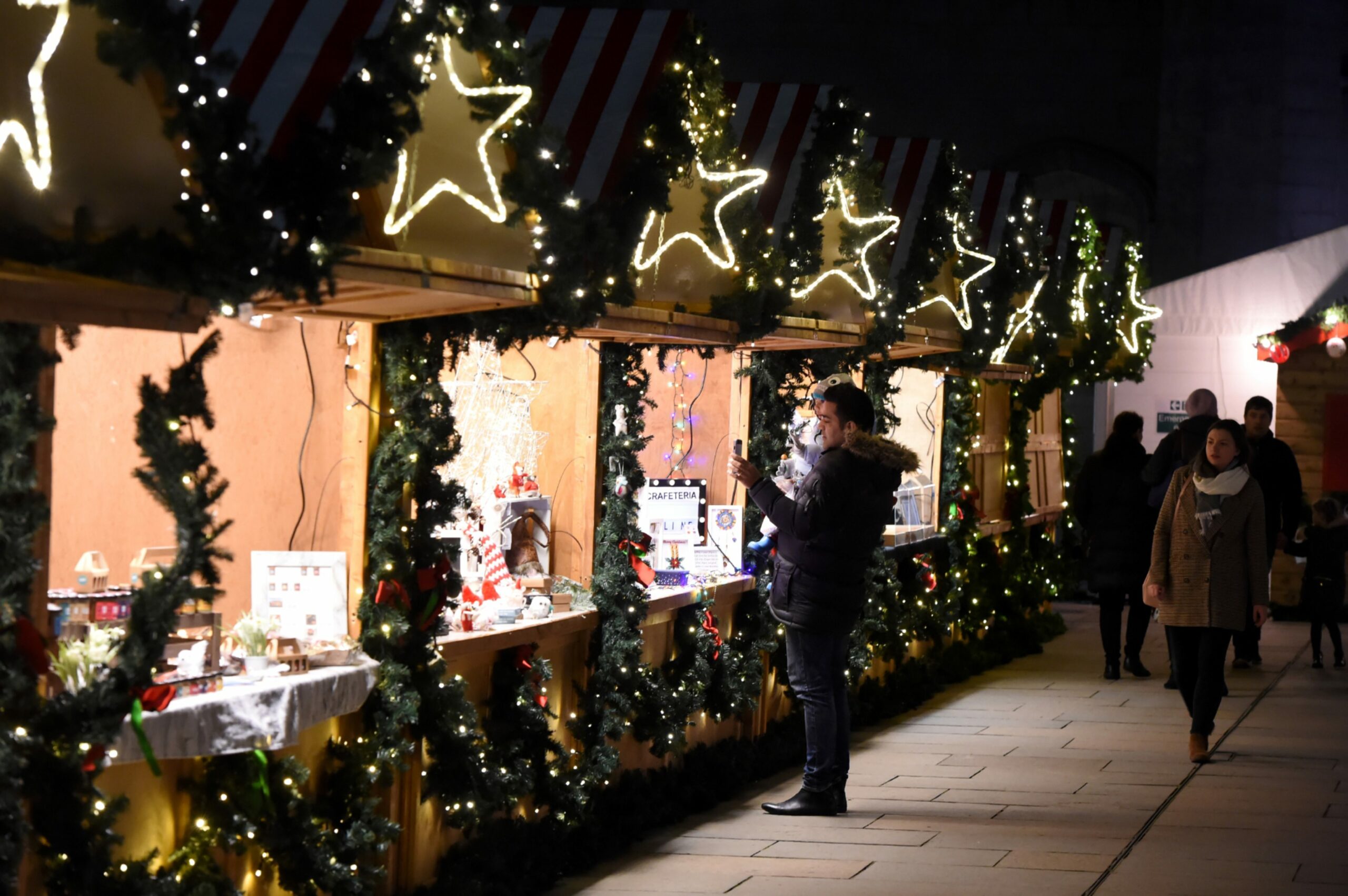 Stalls at Aberdeen Christmas village, decorated with fairy lights and pine branches, where you can shop local this Christmas