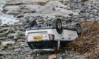 White Land Rover on its roof on Gardenstown beach