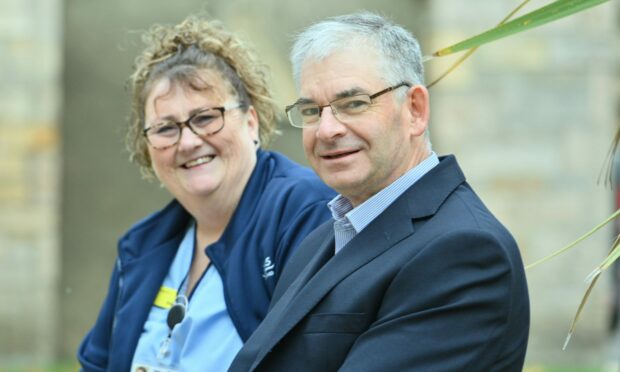 Sue Petrie and Simon Bokor-Ingram sitting outside smiling as they encourage people to join NHS Grampian health and social care roles
