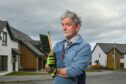 Malcolm Bradley with a dustpan brush outside Irene Moffatt's house in Elgin