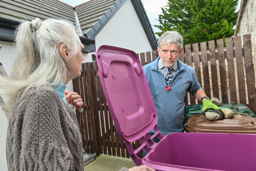 Malcolm Bradley putting things in the bin and speaking to Irene Moffatt who he is doing a job for today