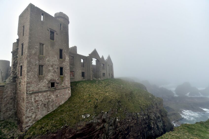 Slains Castle as fog slightly hiding the hills and walls in the distance. 