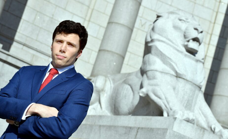 Ryan Houghton posed with arms crossed in front of Aberdeen's War Memorial Lion.