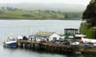 A fish feed barge sunk off Portree Harbour during 2021 winter storms remains on the seabed after emitting noxious fumes in August. Image: Sandy McCook/ DC Thomson