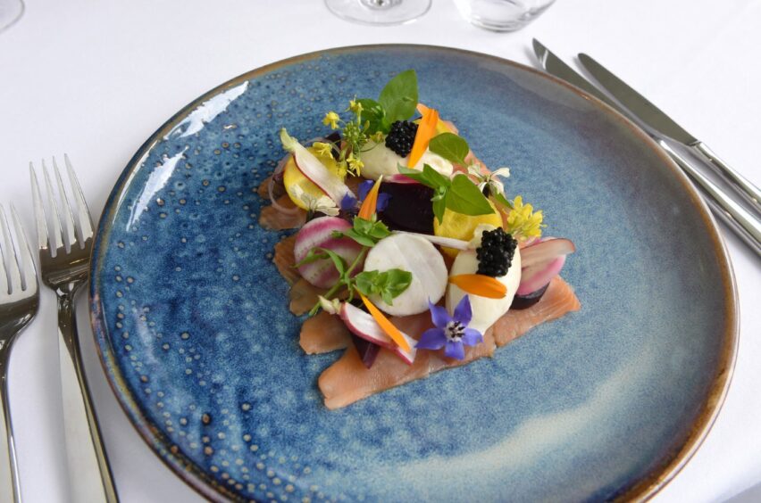 A blue plate with Citrus infused salmon with pickled vegetables.
