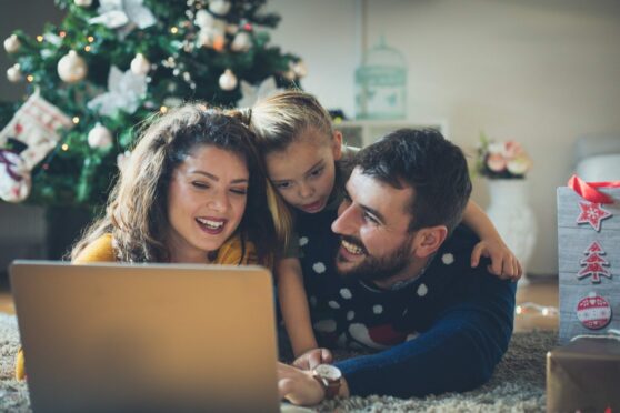 Family planning their Christmas events in Aberdeenshire in front of a Christmas tree.