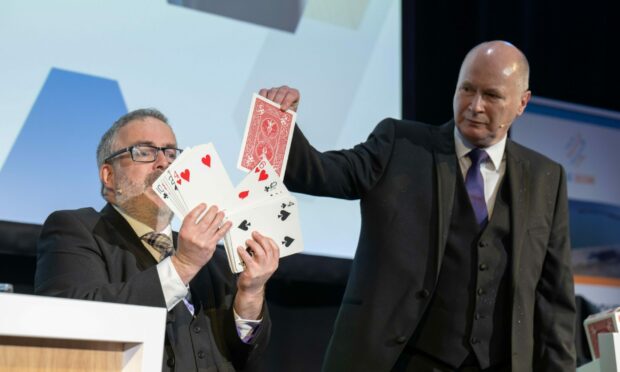 Magician Ivor Smith takes a card from Jeff Burns during a performance. Image: Jonathan Addie/Michal Wachucik/Abermedia.