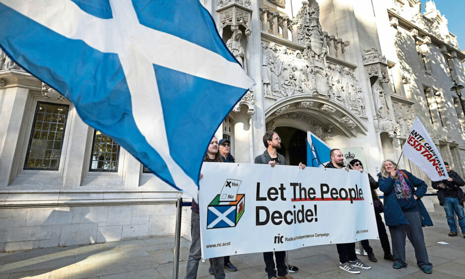 Indyref2 campaigners holding a banner reading "let the people decide"