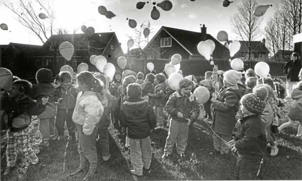 The sun shining over a group of children releasing balloons into the air in celebration of the nursery turning 10 years old