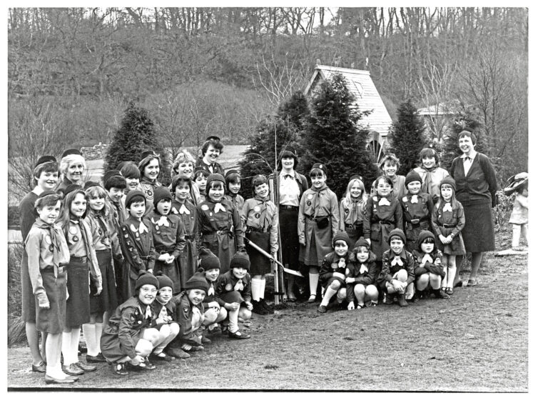 A group of girl guides with their leaders surrounding a tree being planted on their anniversary