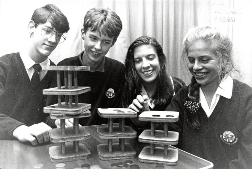 Four students, two boys and two girls, trial a board game they invented