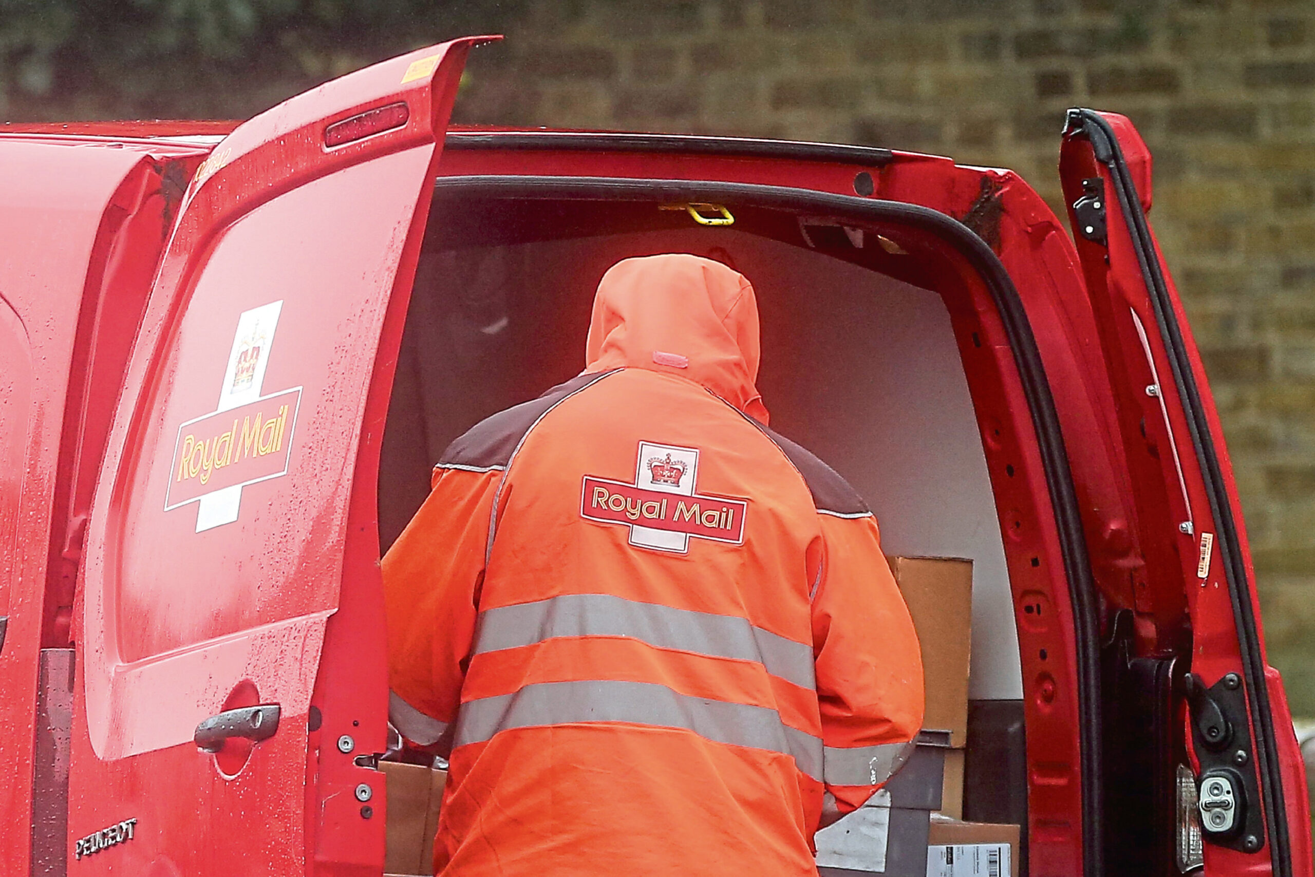 Back of Royal Mail worker in rear of post van. 