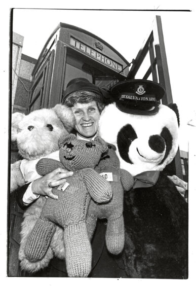A commanding officer holding four teddy bears, including a panda bear in a Salvation Army hat