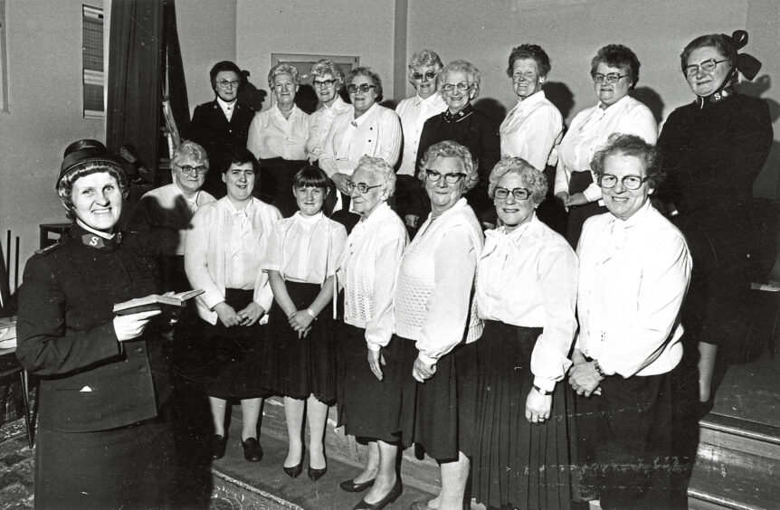 A group of mainly elderly women standing two rows