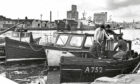 1978 - Fishermen have a chat at Waterloo Quay while two big oil vessels loom large in the background.