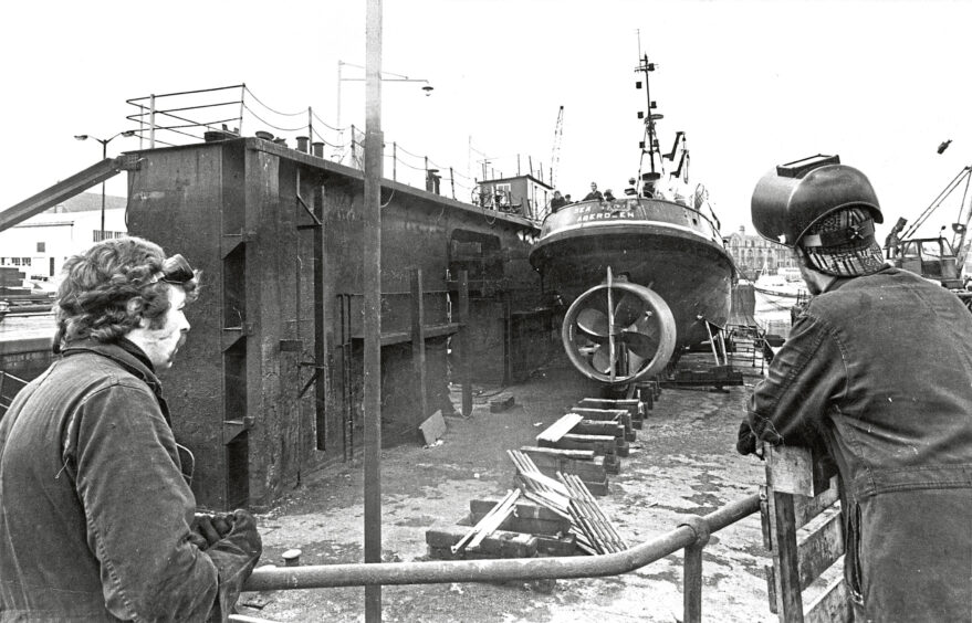 1978 - Andy McTurk and Steve Mitchell look on as the tugboat Sea Trojan harbours into the number 1 pontoon dock following dredging work. 