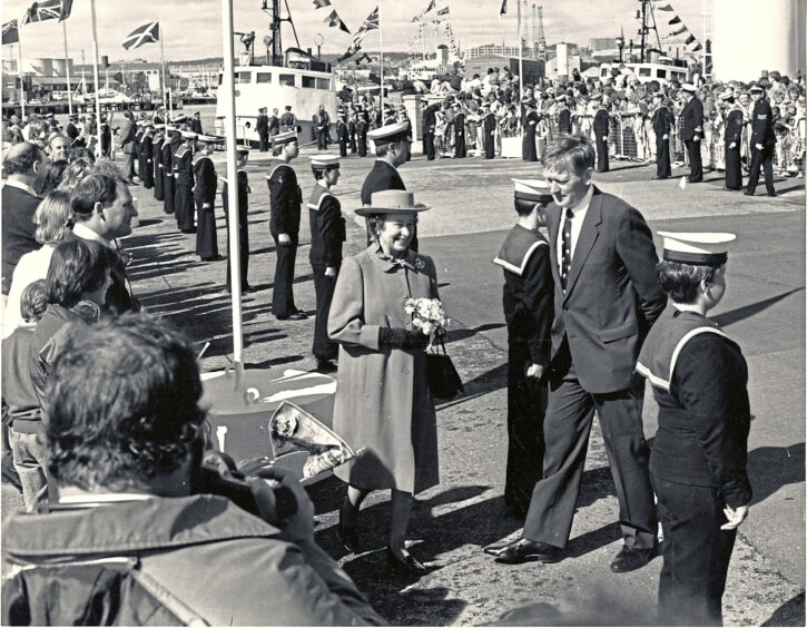 1986 - Sea cadets line the route as the smilling Queen walks along the quayside, accompanied by Aberdeen Harbour Board chairman Mr John Cradock.