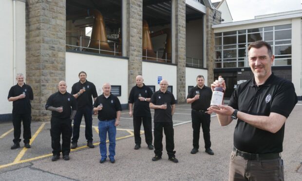 Aultmore Distillery workers holding a bottle