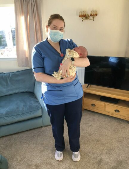 Midwife Lucy Peat enjoys a cuddle with newborn baby Maggie. 