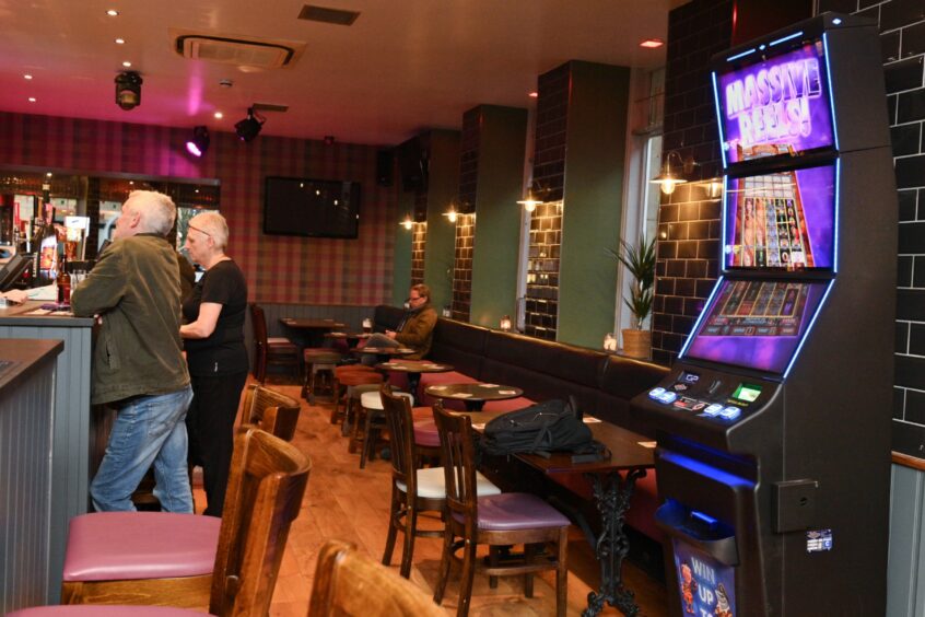 The bar, with a slot machine facing it, next to some tables