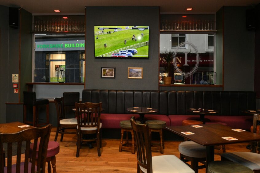 The seating area inside The Imperial Inverness with a view of one of the TVs during a horse race
