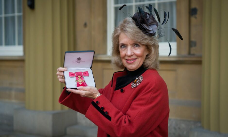 Jeanette Forbes holding her OBE accolade at Buckingham Palace.