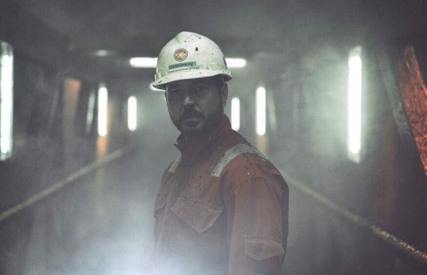 Martin Compston wears a hardhat and PPE in a scene from Amazon Prime Video's The Rig 