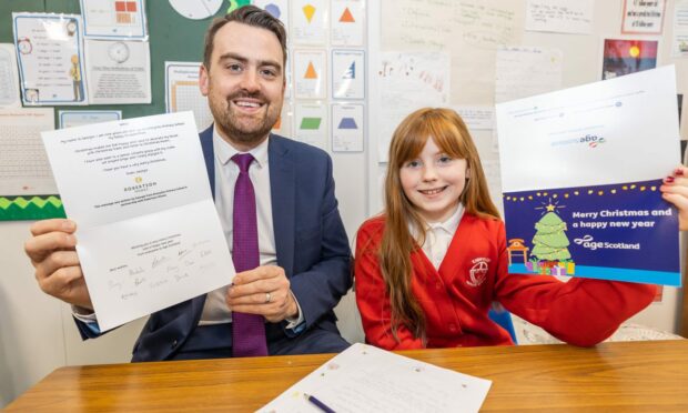 Kinmylies pupil Georgie Gilham with the Age Scotland Christmas card featuring her letter, pictured with Graeme MacPherson, Senior Sales Executive at Robertson Homes