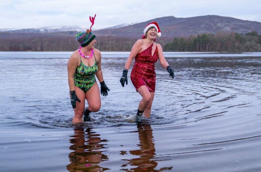 Members of the Loch Insh Dippers wild swim group take part in a Christmas-themed swim in Loch Insh in the Cairngorms National Park near Aviemore, Scotland. Picture date: Friday December 23, 2022. PA Photo. Photo credit should read: Jane Barlow/PA Wire