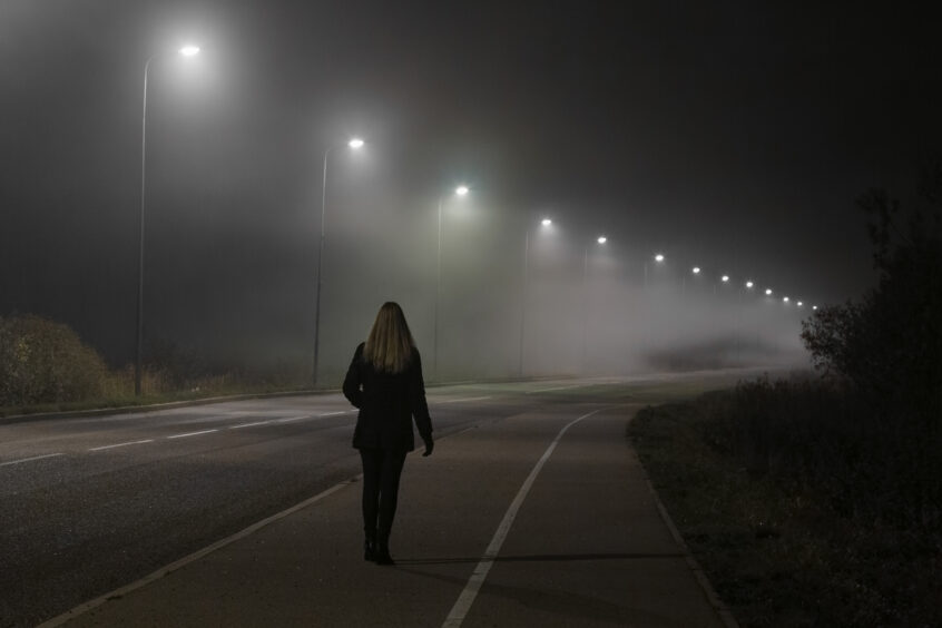 Photo of woman walking alone in the night.