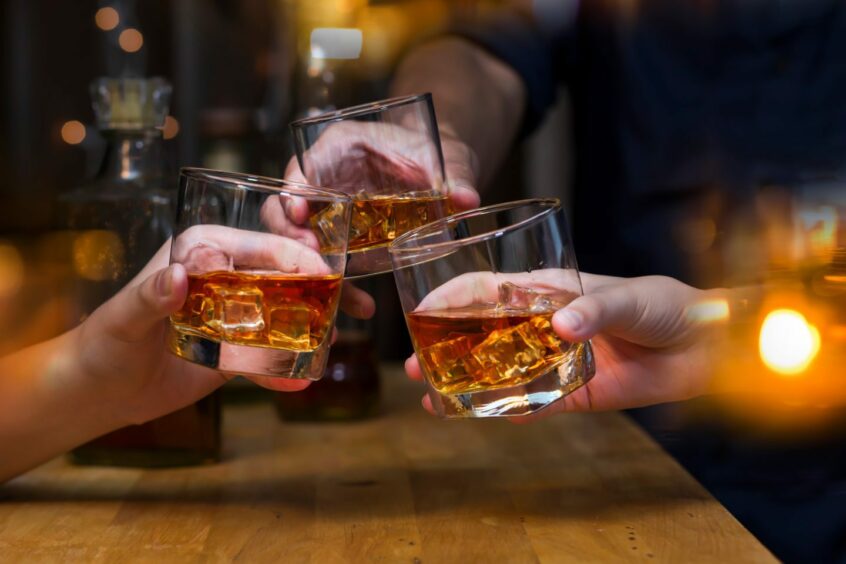 Three whisky glasses being clinked