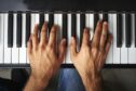 Male pianist's hands playing keys on a piano