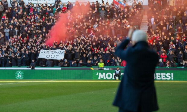 Jim Goodwin applauds the Aberdeen fans at Easter Road ahead of the game at Hibs - as they unveil a "Goodwin Out" banner. Image: SNS