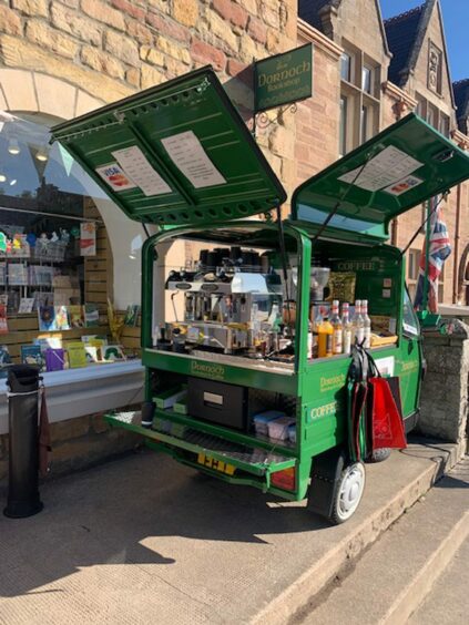 The green Piaggio coffee van with all its doors open and coffee machine on show outside independent Dornoch Bookshop.