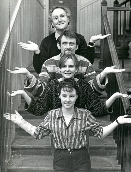 Four actors from Studio Theatre Group standing on a stair each with their hands out forming a shrugging motion