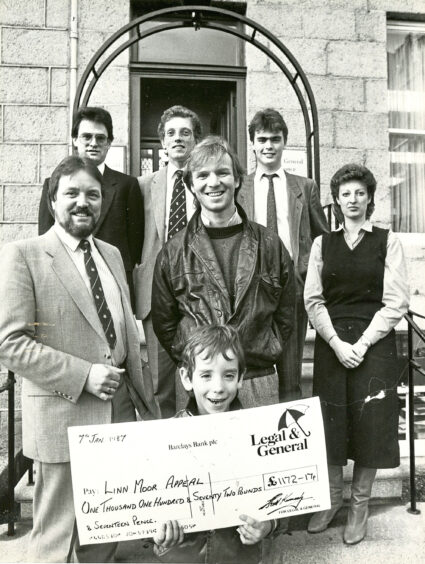 1987 - Dons legend Alex McLeish and his 5-year-old son Jon present a cheque for £1172.17 to the Linn Moor School. 