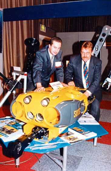 A coloured photo of two men in suits and ties with a display ROV
