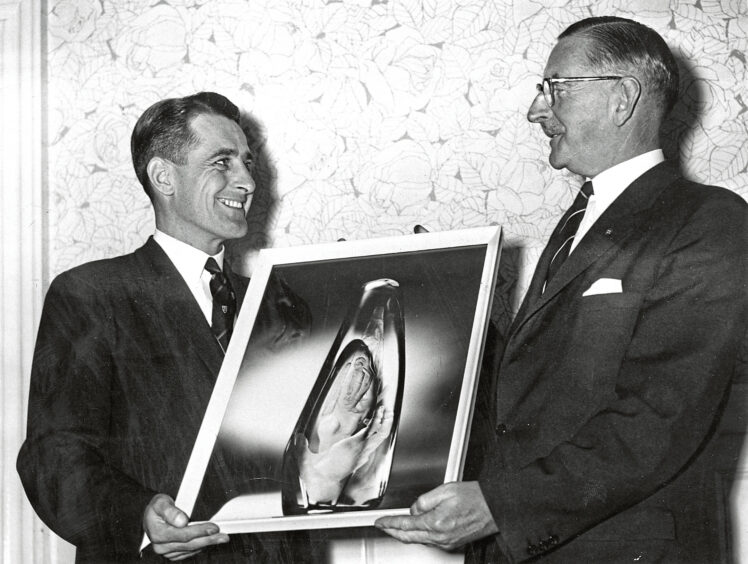Two men holding a photo of an award between them