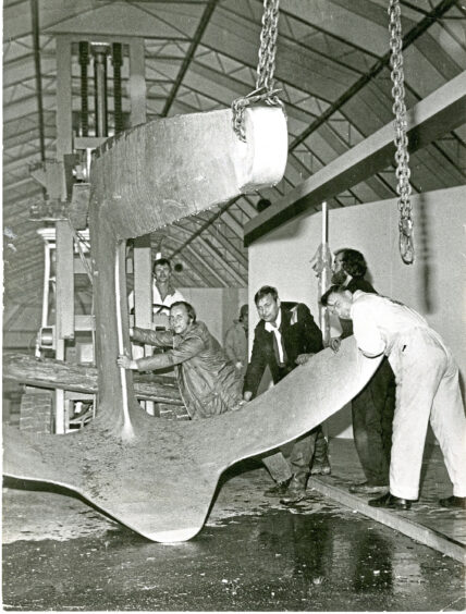 a group of men surrounding a giant anchor