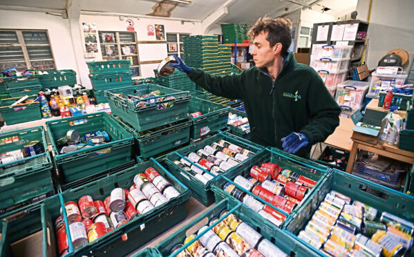 a foodbanks worker with crates of non-perishable food, mainly in cans
