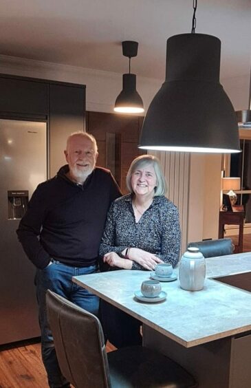 Barbara and Alan Low stand next to one another leaning on the island in Milton View's kitchen. 