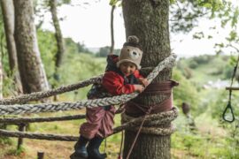 Child playing in trees at outdoor nursery in the Highlands