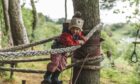 Child playing in trees at outdoor nursery in the Highlands