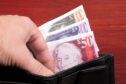 hand taking Scottish money from wallet to possibly buy in north-east Scotland's property market