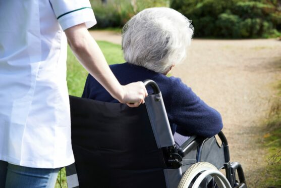 A care worker is pushing a patient in a wheelchair.