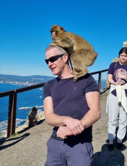 John William Simpson with Gibraltar monkey standing on his shoulders with its hands on his head