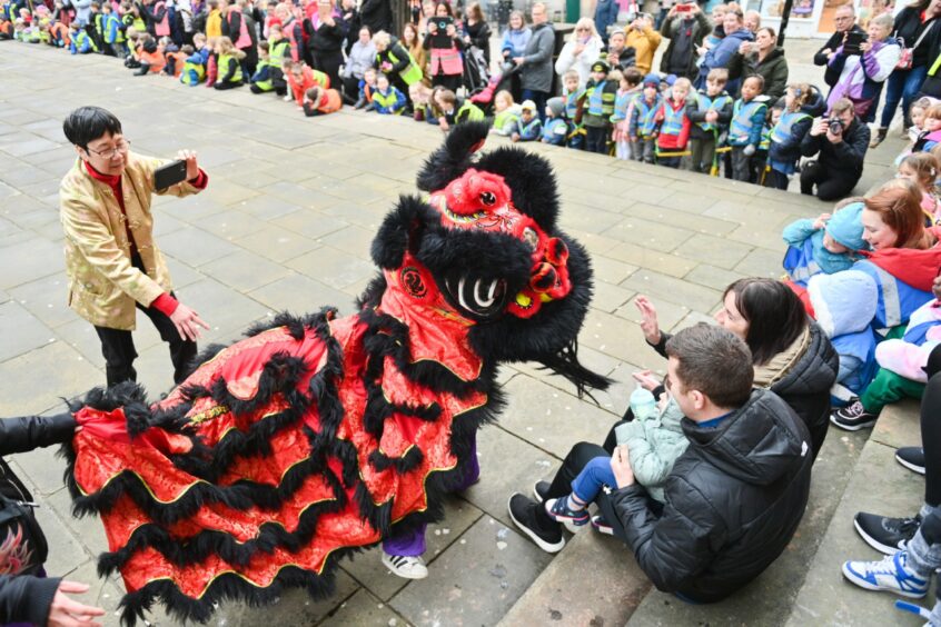 Black dragon going up to people watching the Chinese New Year parade in Elgin 