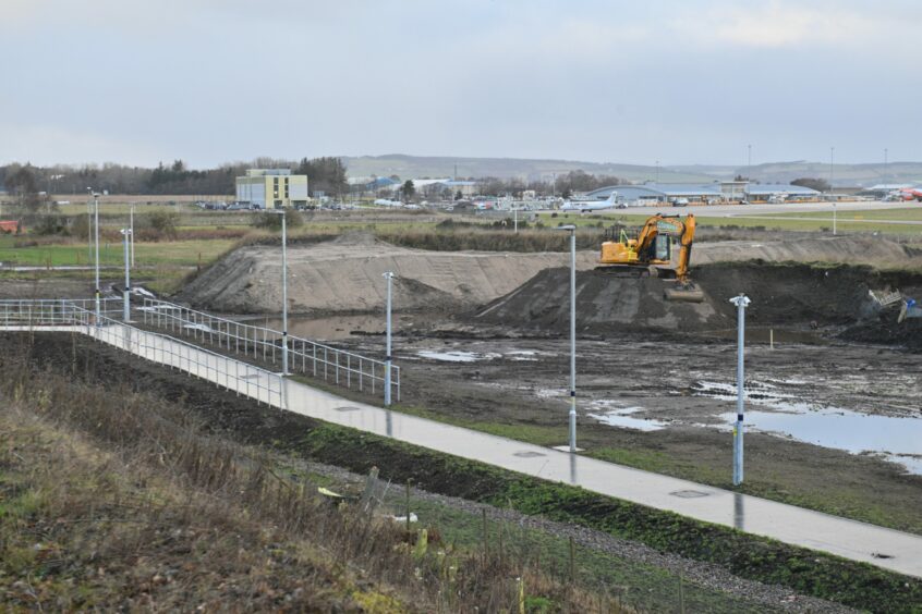 The lit pathway between Inverness Airport terminal and Inverness Airport Railway Station, while works continue in the background. 